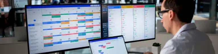 Healthcare IT professional managing EHR optimization on dual monitors displaying scheduling and workflow dashboards.